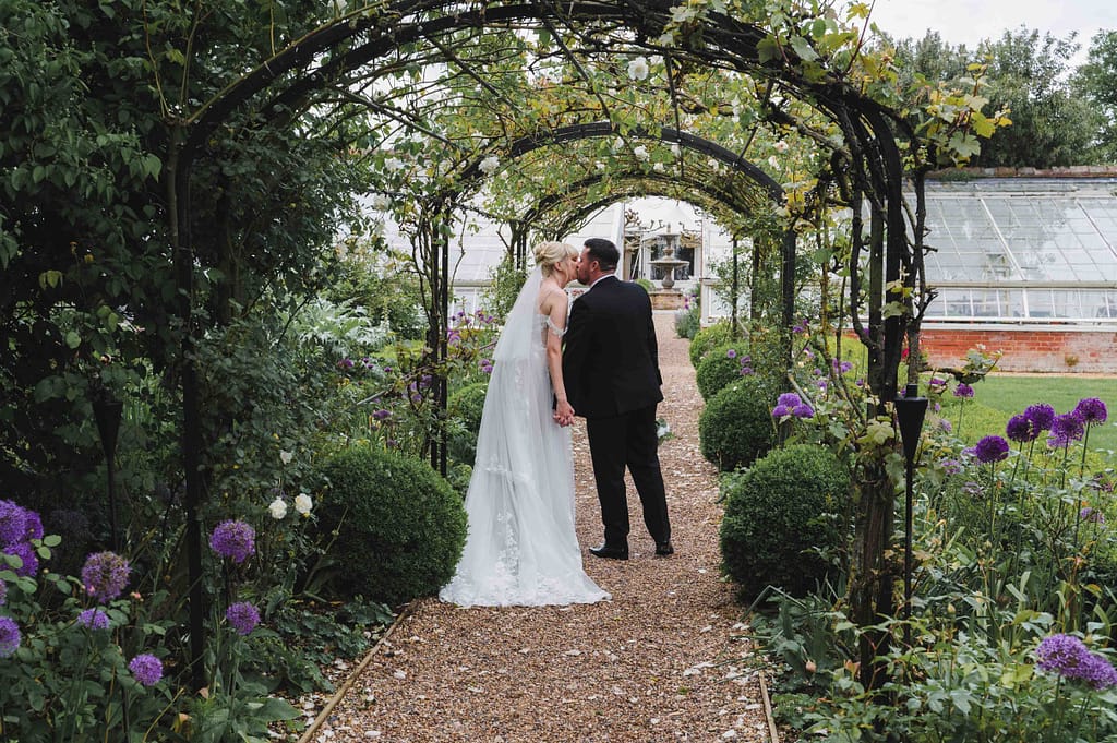 Bride & Groom kissing in the gardens at Braxted Park wedding venue