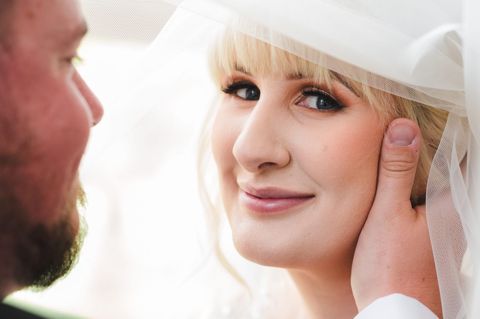 Professional Wedding Photographer - A close up of a bride and groom, the groom is gently touching the bride's face