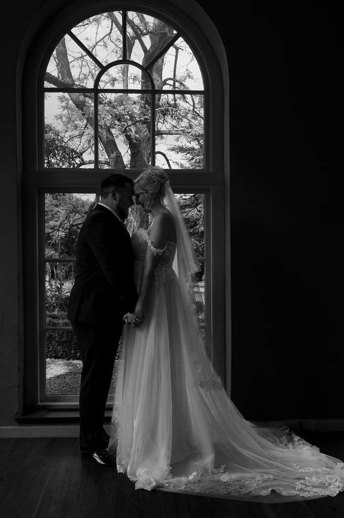 Newly married couple in front of the window in the Orangery at Braxted Park