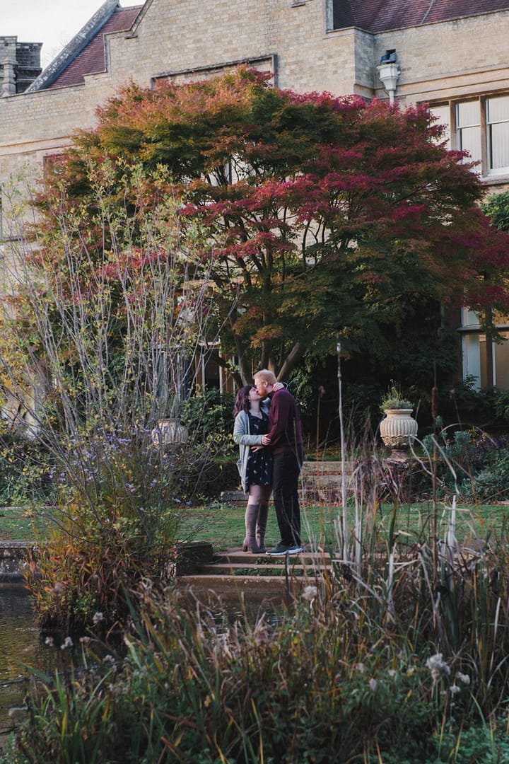 A couple in the grounds of a large house kissing